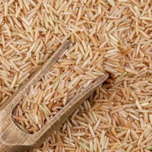 Detailed close-up of organic brown rice grains with a wooden scoop showcasing texture and natural colors.