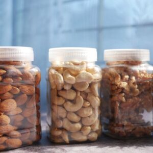 Vibrant display of almonds, cashews, and walnuts in plastic jars on a kitchen countertop.